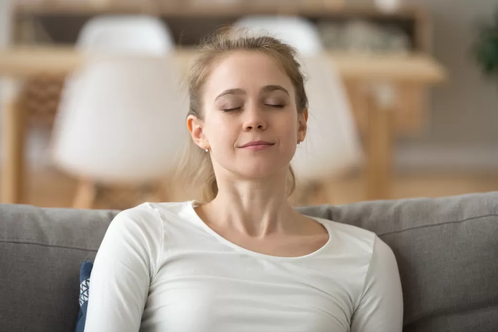 Close up calm peaceful woman relaxing with closed eyes on sofa